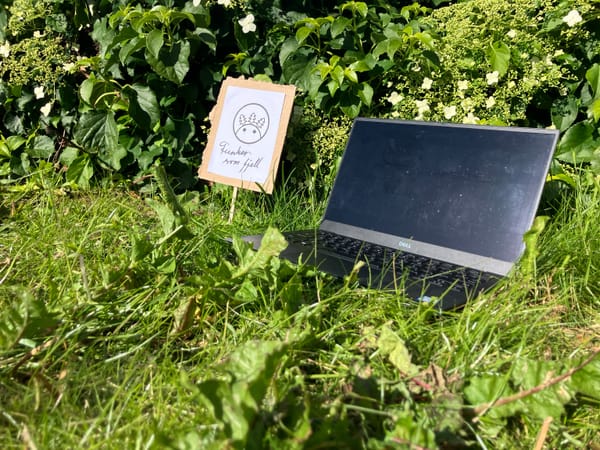 PC som ligg i gras ved siden av ein plakat der det står Funker som fjell